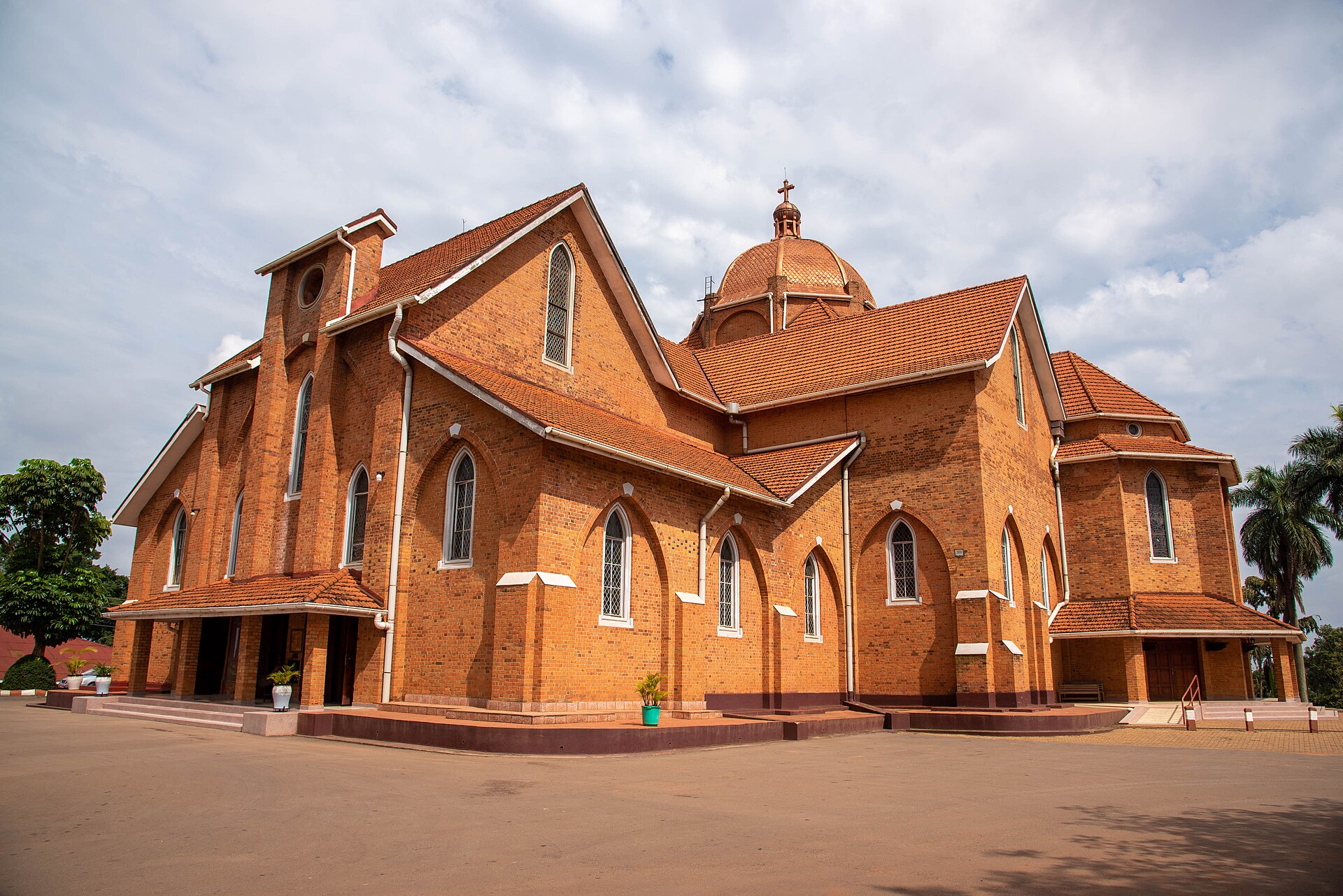 Namirembe Cathedral, a red-brick cathedral with a dome, seen across its paved forecourt.